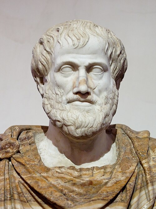Marble bust of Aristotle, depicting a bearded man with wavy hair and a serious expression. He is wearing a draped robe, and the sculpture displays detailed features highlighting Greek artistic style.