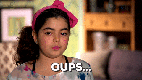 Young girl with a pink headband looks slightly embarrassed, sitting indoors with a blurred background, and the word "Oups..." appears at the bottom.