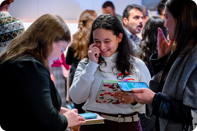A group of women share contact information at a networking event.