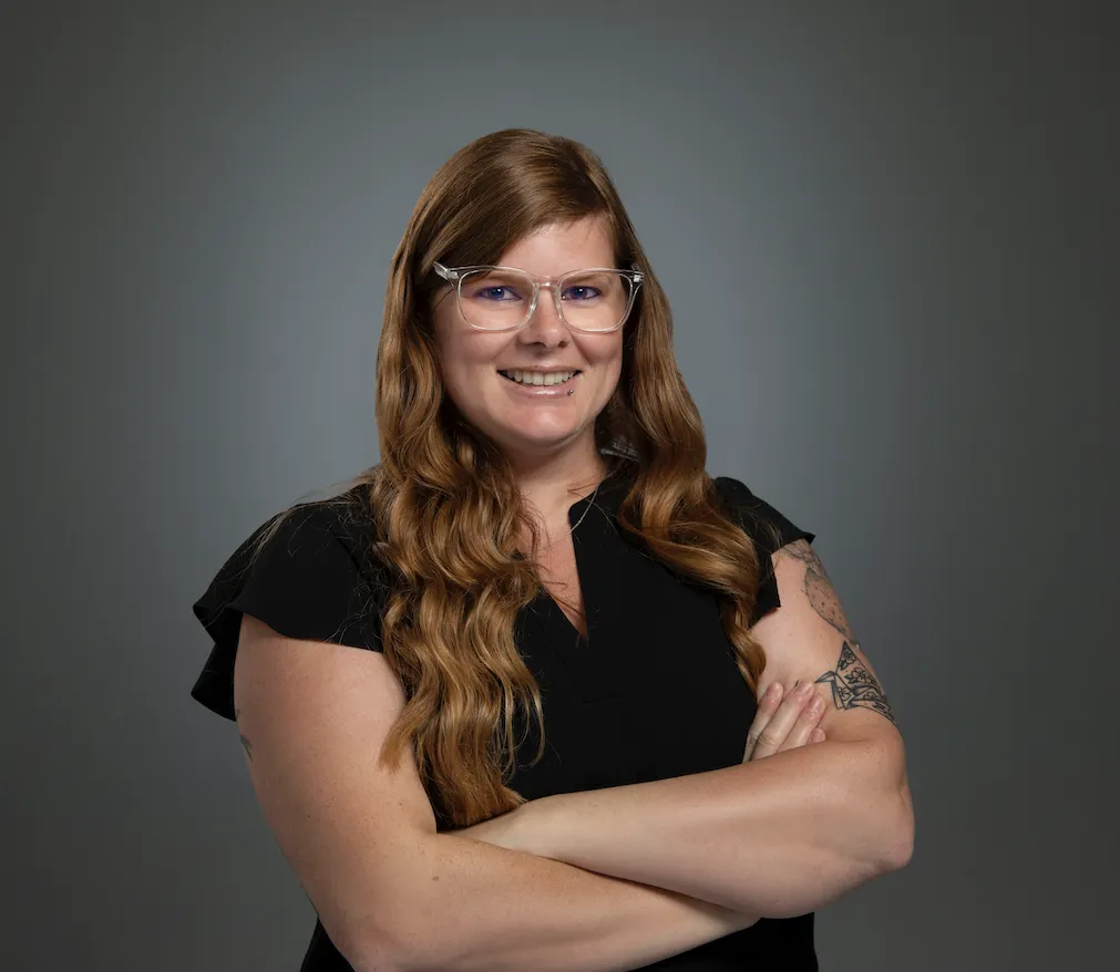 Holly V. smiles in her headshot. The photo is emphasized by a bright pink drop-shadow.