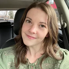 Holly V. smiles in her headshot. The photo is emphasized by a bright pink drop-shadow.