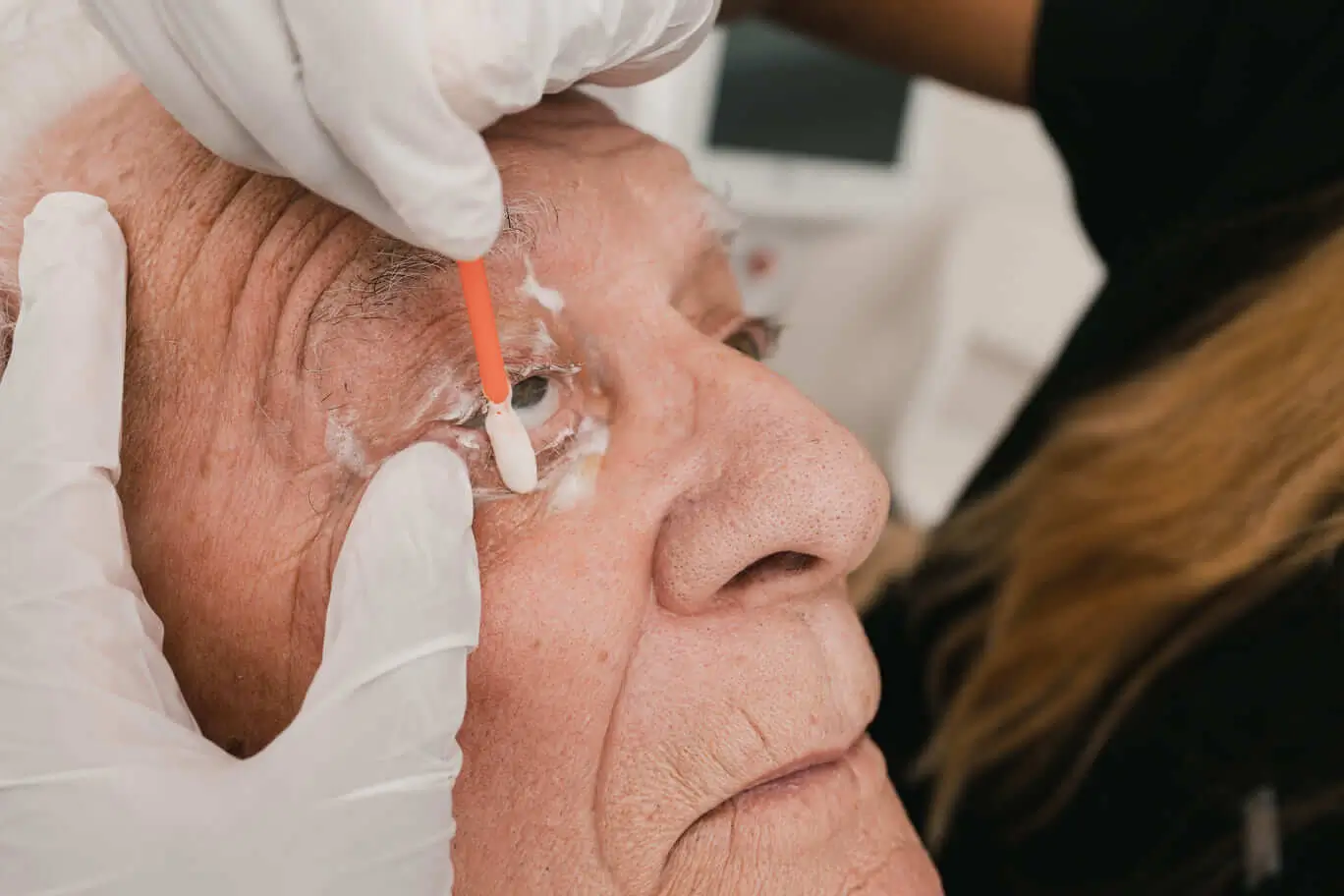 A woman is cleaning a man eyelashes