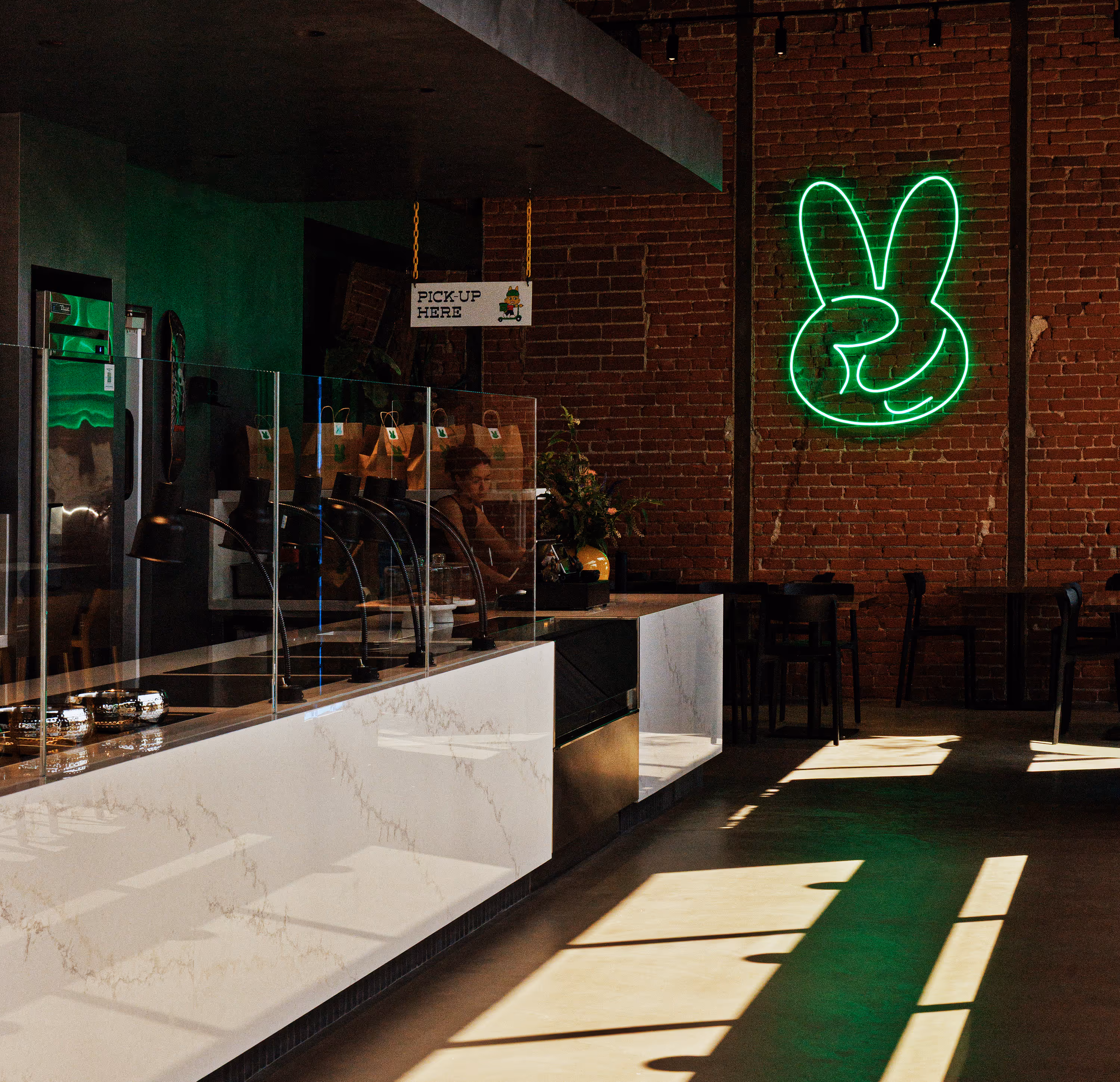 Fast-casual ordering counter displaying fresh Chinese American dishes in Los Angeles, with Jade Rabbit neon logo on the wall