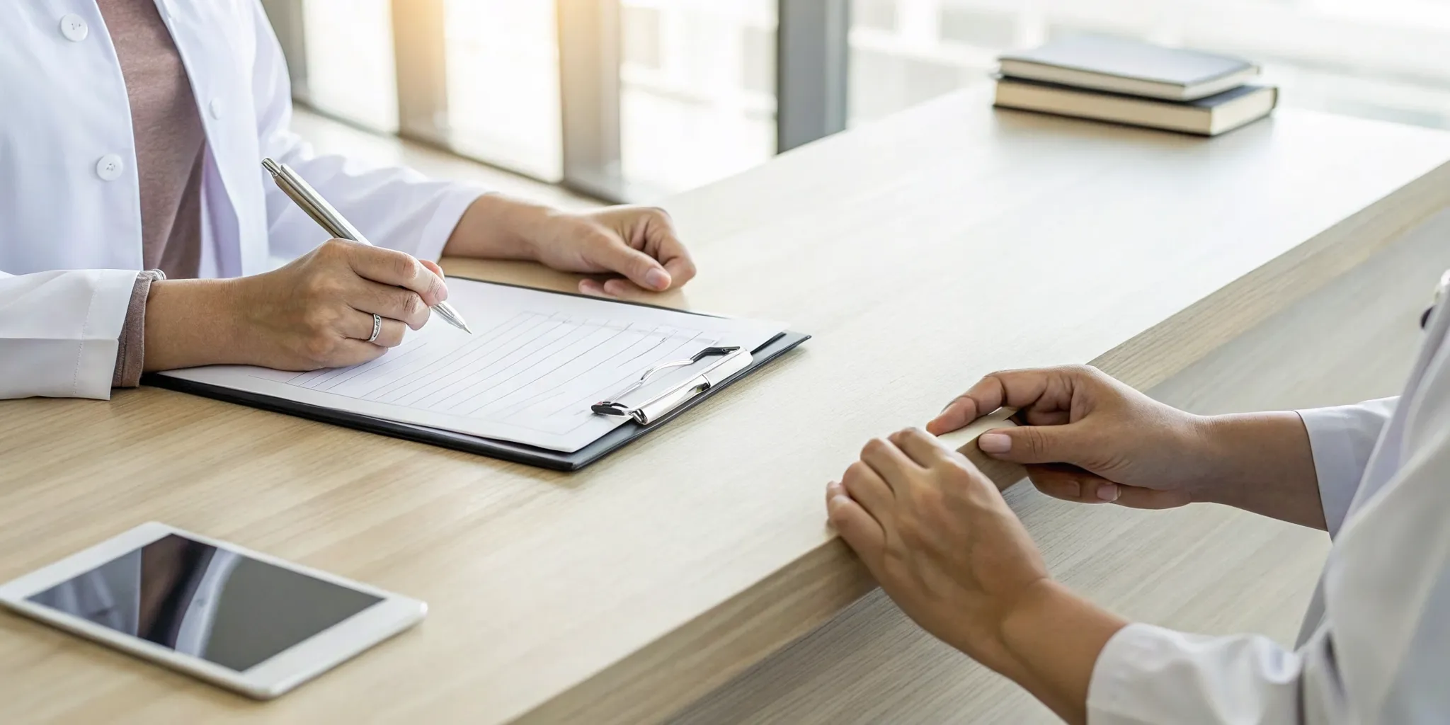 Doctor providing help to a patient with overwhelming medical paperwork at a desk.