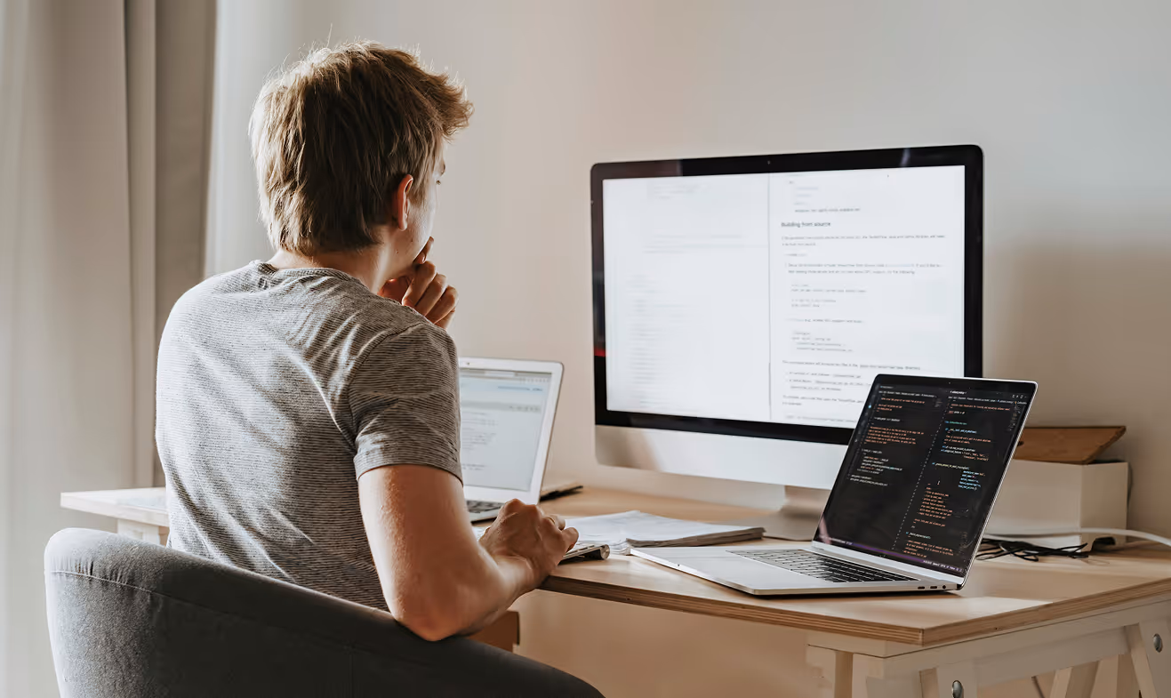 Man looking at his computer screens with code on them
