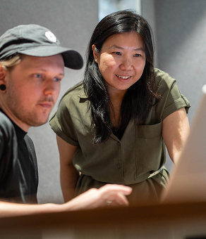 Two Q-CTRL colleagues, a man in a cap and a woman in a green shirt, looking at a laptop screen indoors.