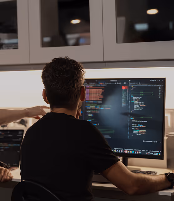 Q-CTRL colleagues collaborating on coding displayed on a large computer monitor in a modern office setting.