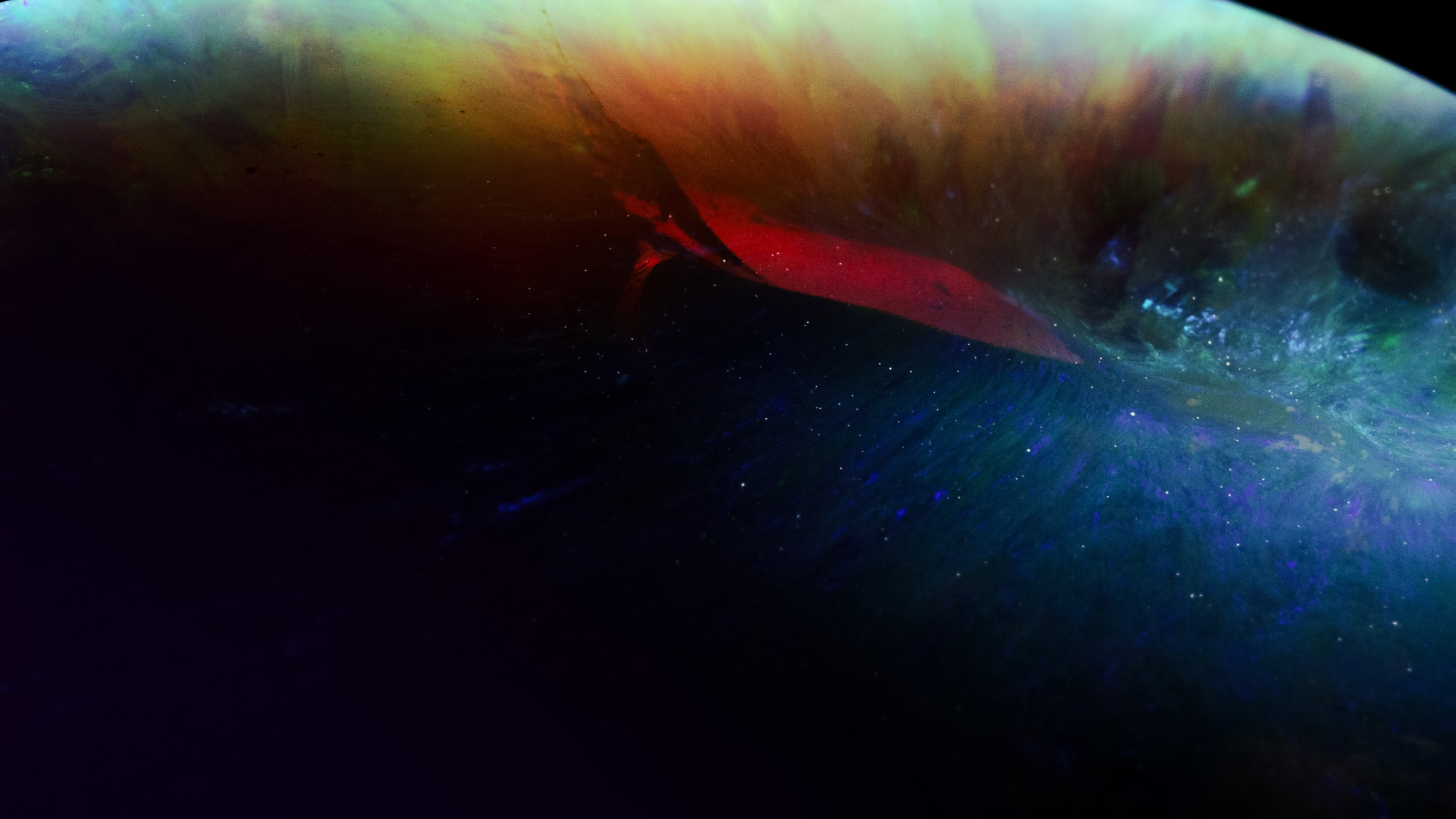 Close-up of a black opal showing vibrant iridescent colors including blue, green, red, and yellow.