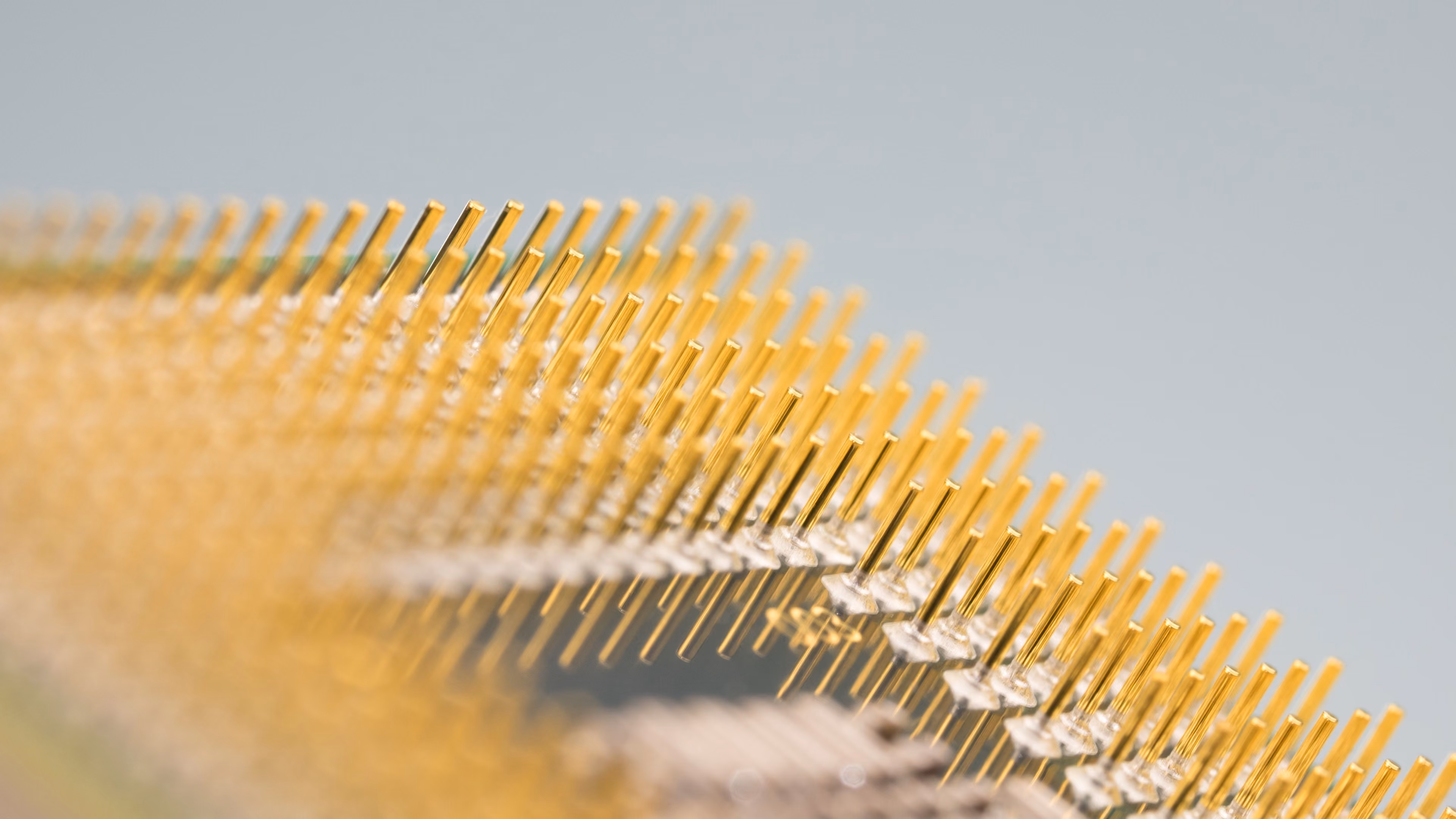 Close-up of gold pins on a computer processor chip against a light gray background.