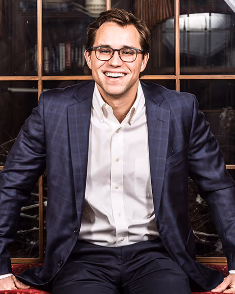A realtor, Taylor Bailey, smiling in front of a bookcase.