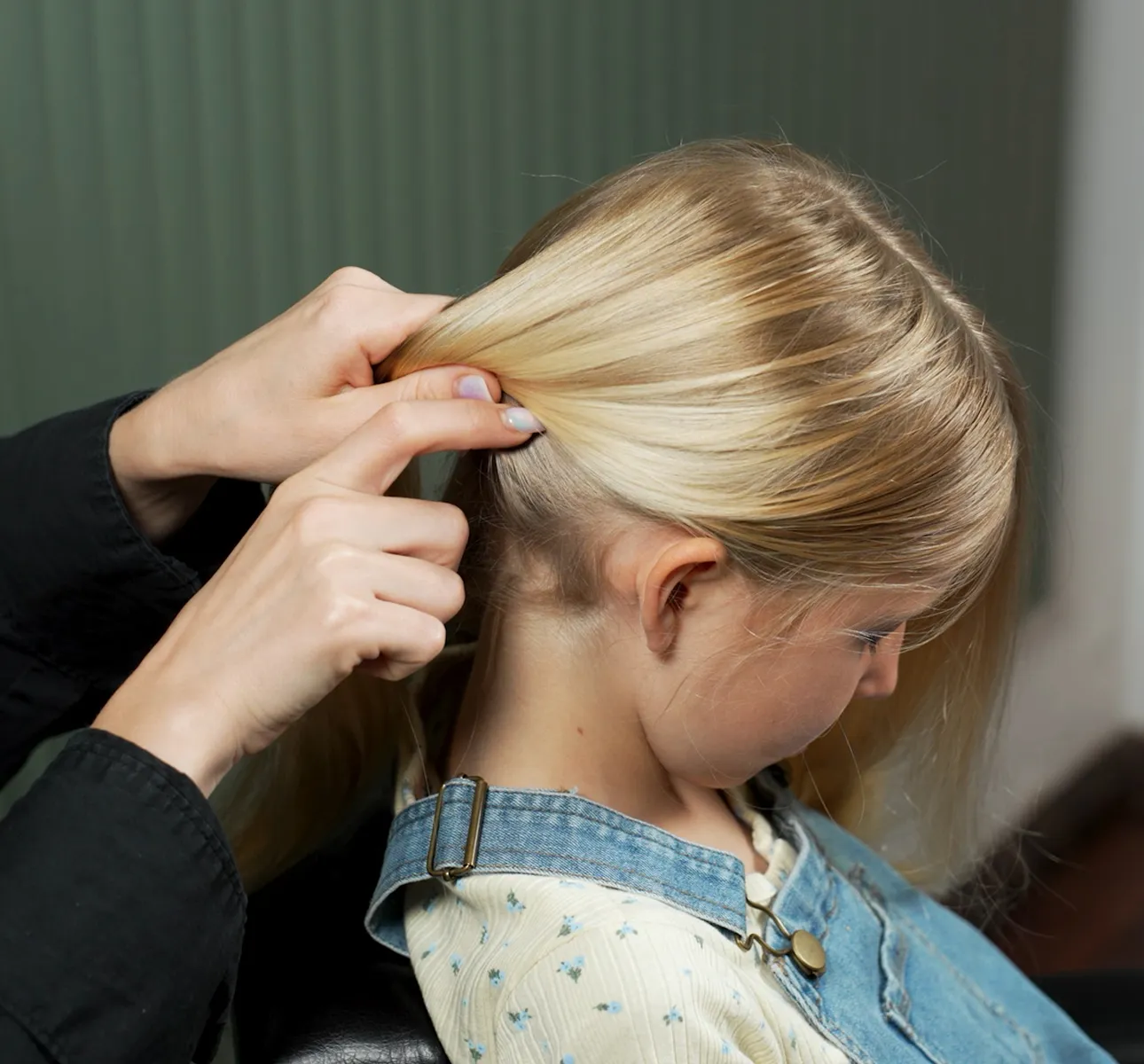 Hands showing hair sectioning technique on a child.