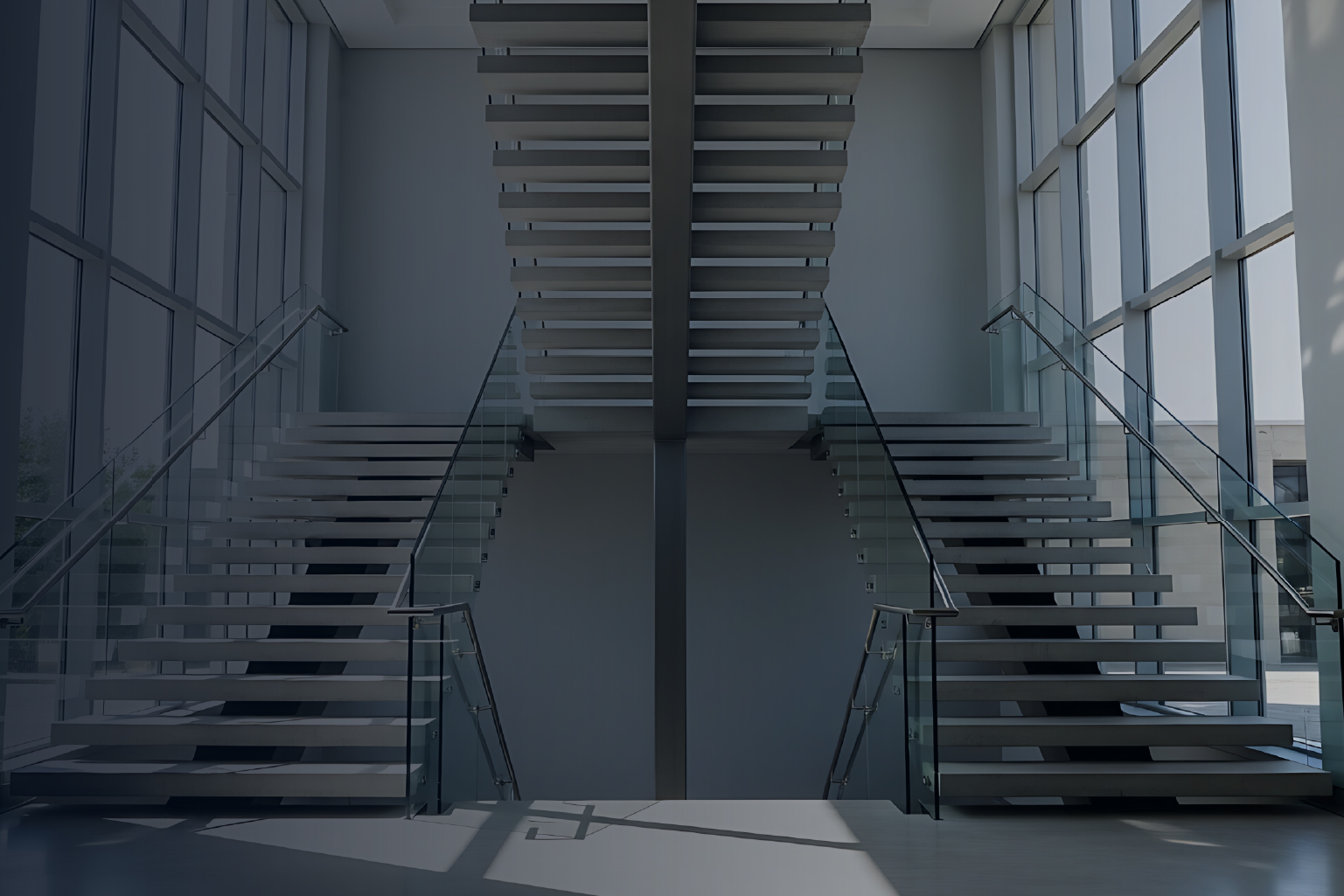 Modern interior featuring a symmetrical floating staircase with glass railings, large windows on both sides, and sunlight casting shadows on the floor.
