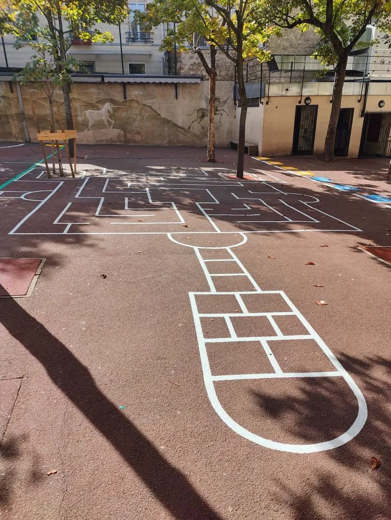 Marelle et labyrinthe peints au sol dans une cour d’école