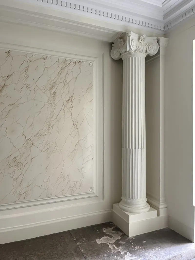 Colonne ionique cannelée et panneau en faux marbre, hall d'immeuble rénové à Paris