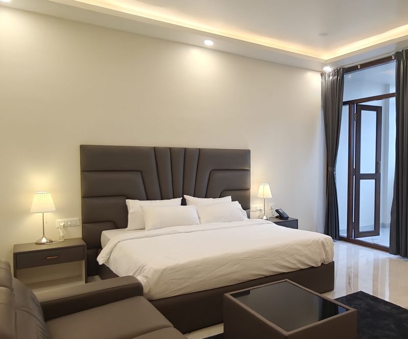 Furnished hotel room with bed, wood panelling and dressing area in North Bangalore