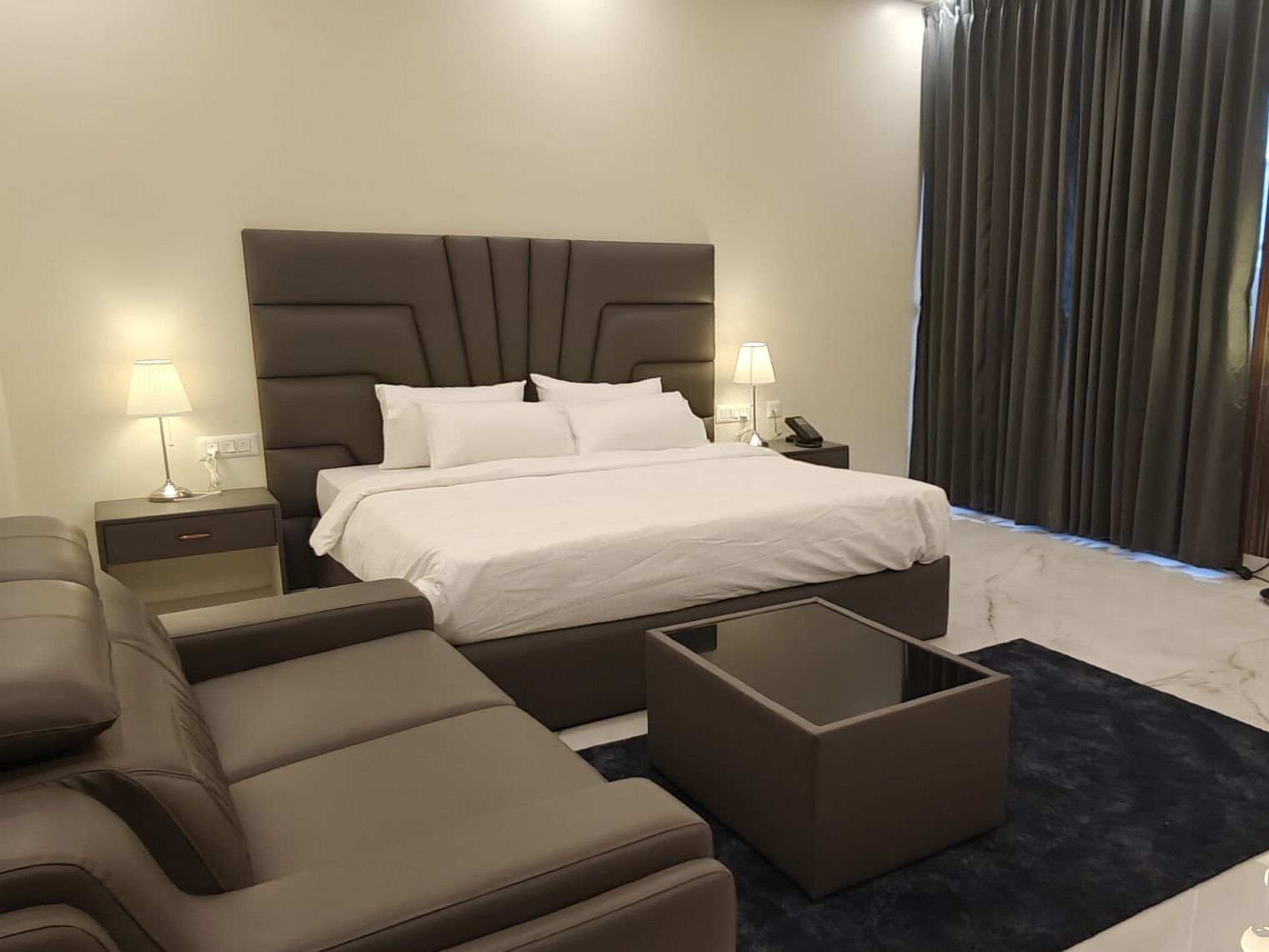 Hotel room with a leather sofa, bed and dressing area near Manyata Tech Park