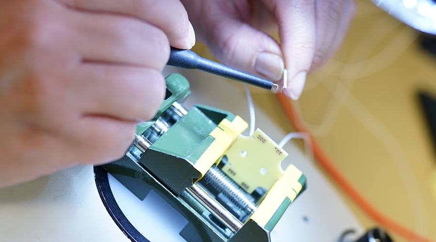 Close-up of persons hands, working at Innokas manufacturing operations. Electromechanical device assembly.