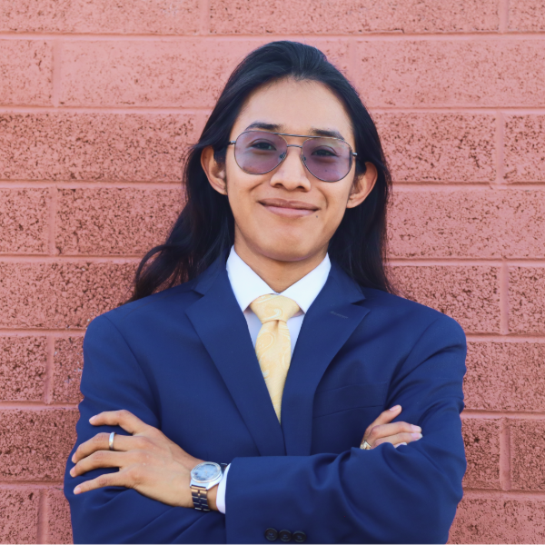 Primer plano de un hombre sonriendo sobre fondo blanco. Lleva camisa negra y gafas.