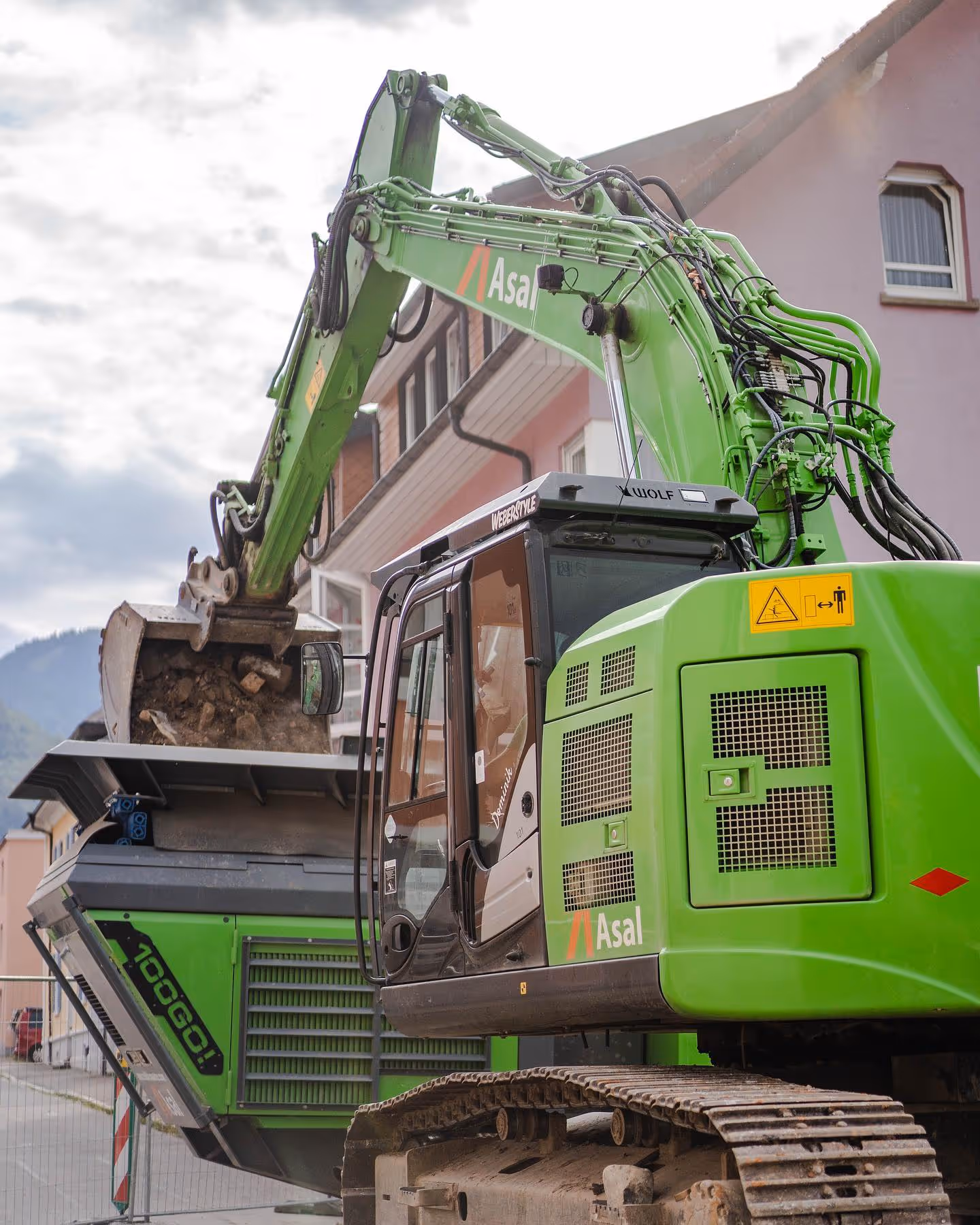 Bagger füllt Brechanlage mit Bauschutt, Recycling auf innerstädtischer Abbruchbaustelle.