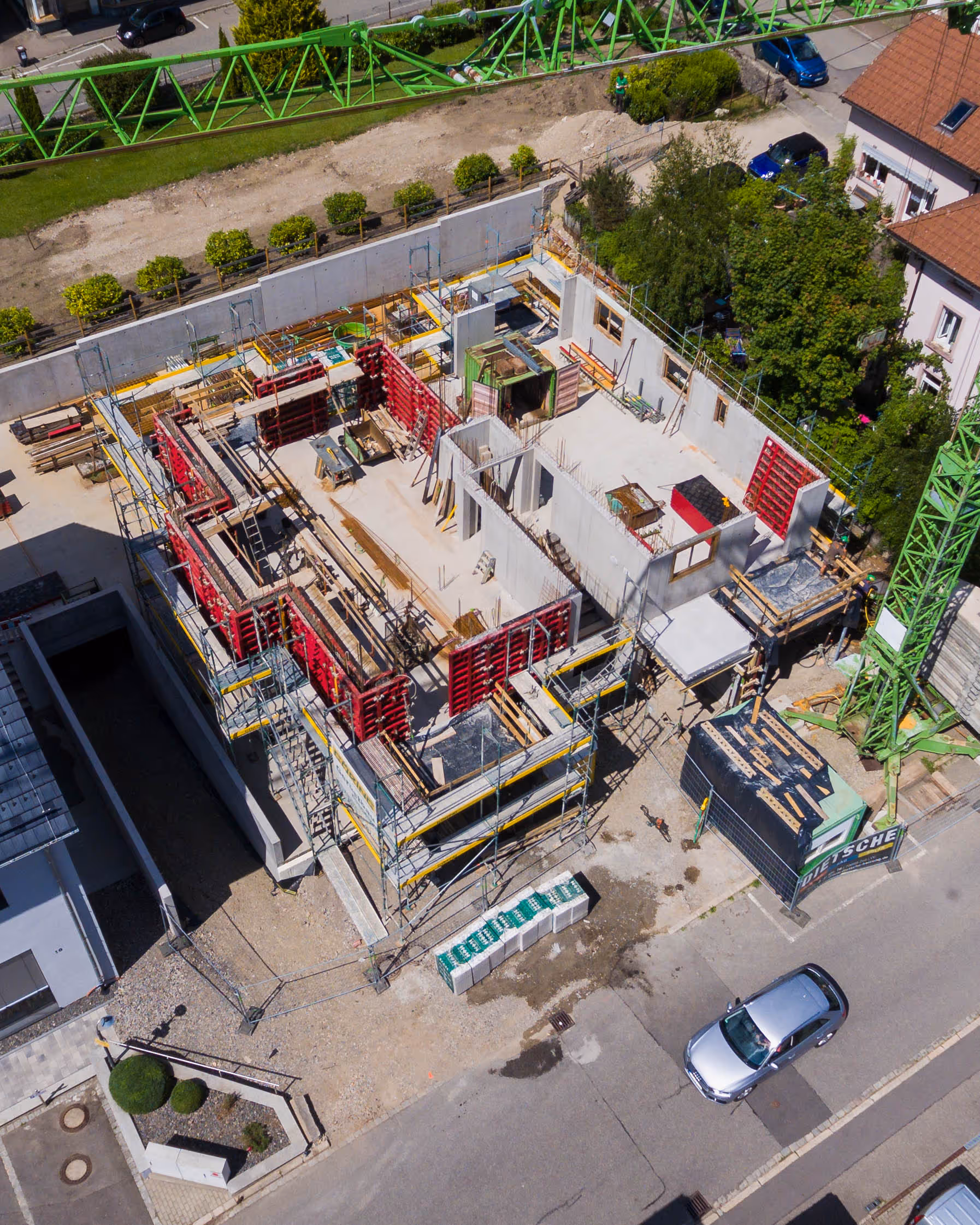 Rohbau eines mehrstöckigen Gebäudes mit roten Schalungselementen.