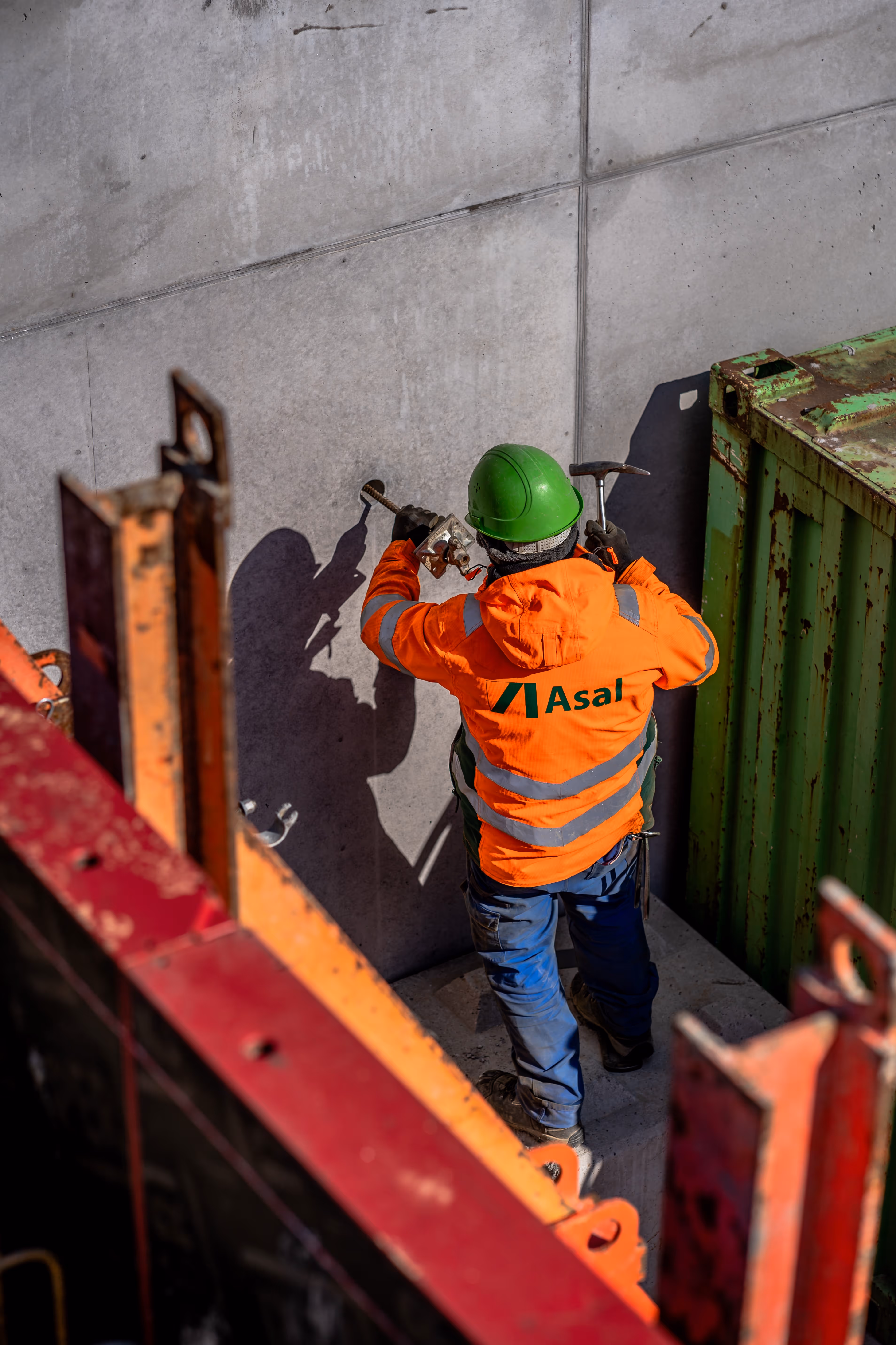 Luftaufnahme einer Baustelle mit bereits errichteten Betonwänden und eingerüstetem Rohbau.