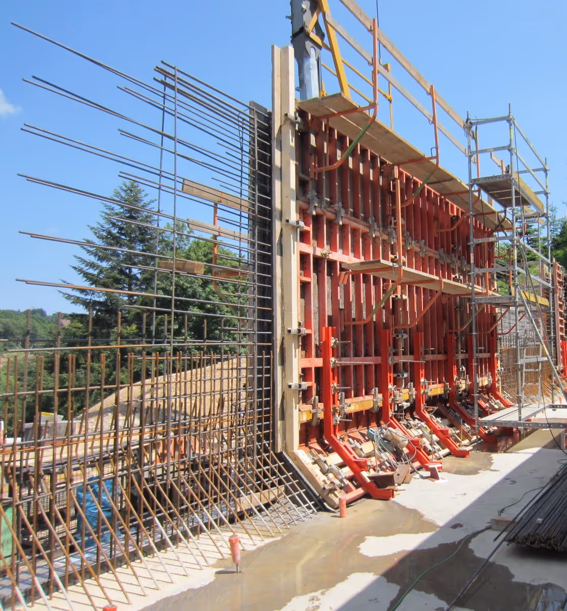 Bewehrungsarbeiten und Schalung für große Betonwand auf Baustelle.