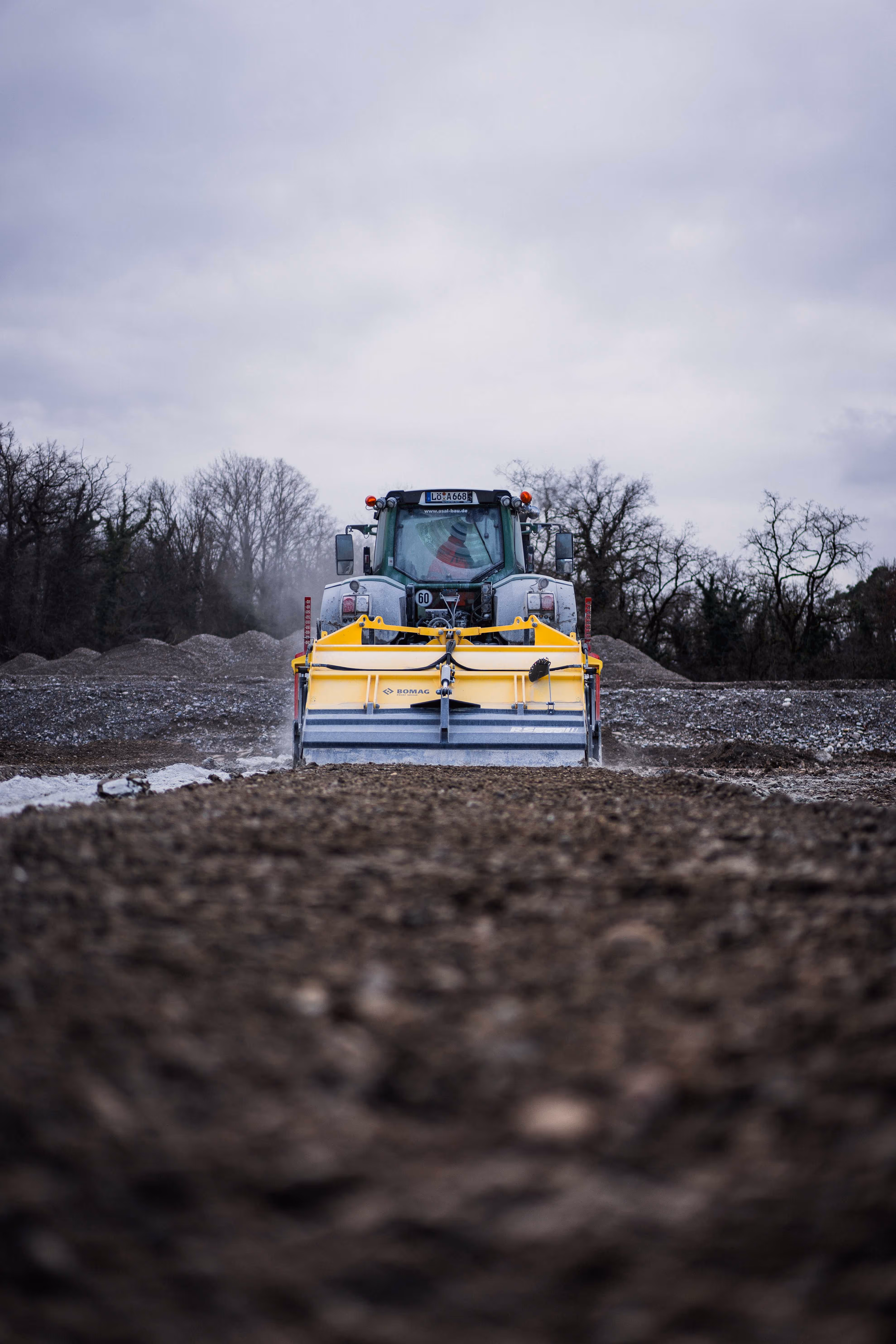 Traktor mit Bodenstabilisierungsgerät auf Baustelle. 