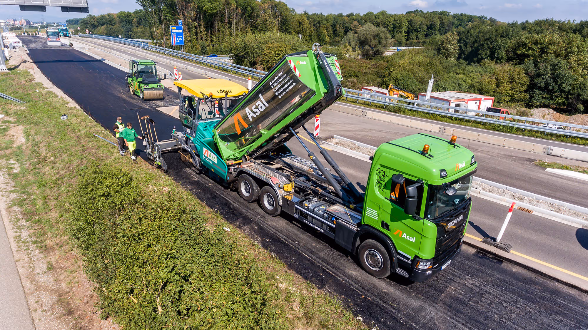 Straßenbauarbeiten auf Autobahn, Asphaltfertiger und LKW im Einsatz