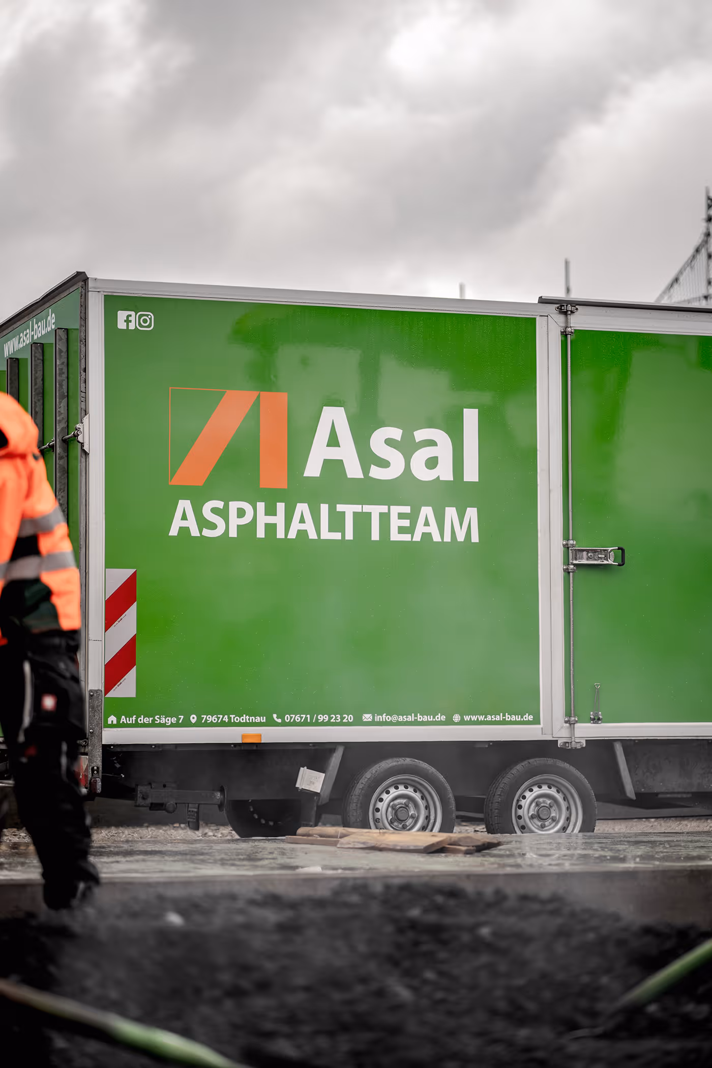 Anhänger mit Aufschrift Asal Asphaltteam auf der Baustelle