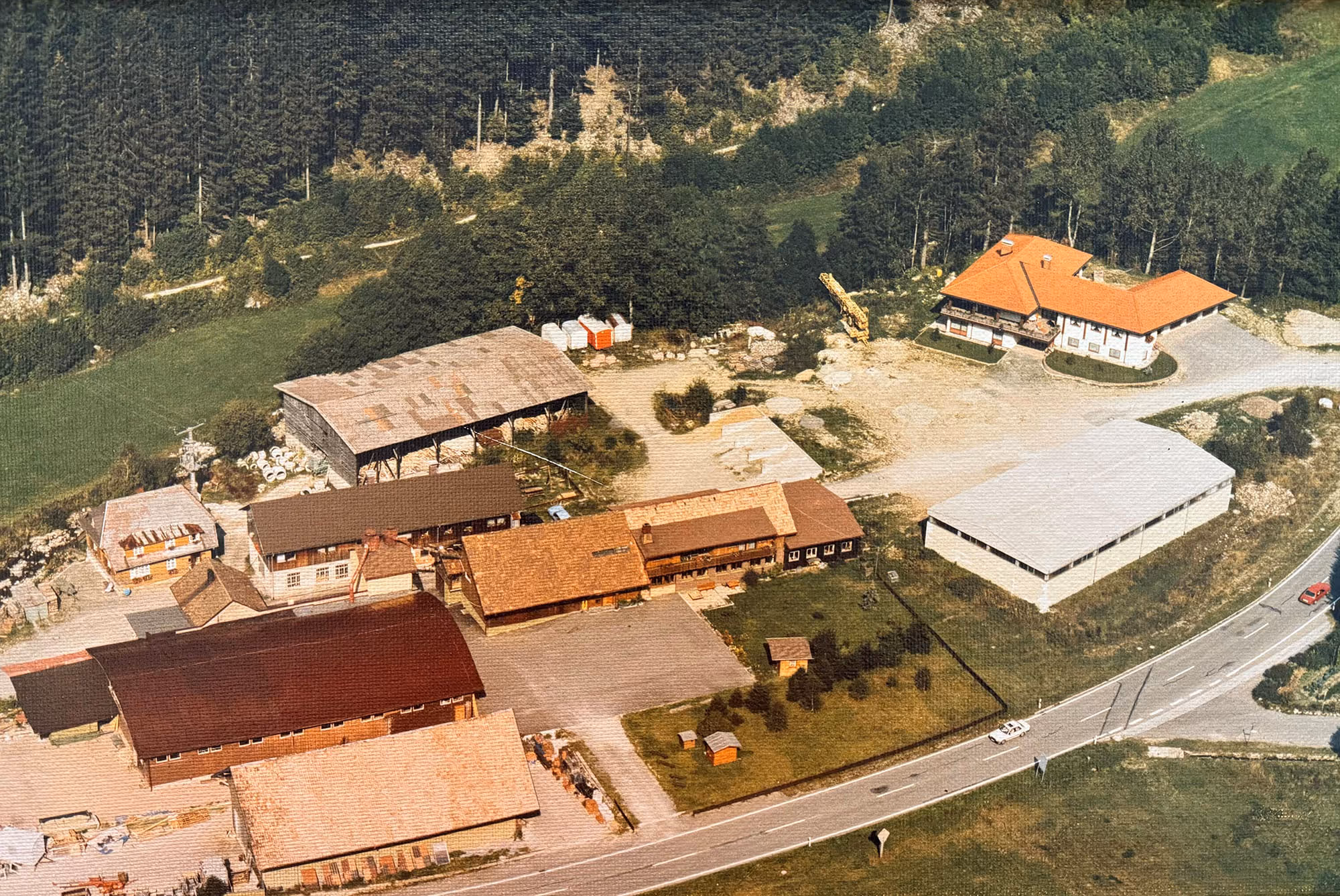 Altes Bild vom Bauhof der Firma Asal mit verschiedenen Gebäuden, Hallen und Lagerflächen, umgeben von Wald und Wiesen.