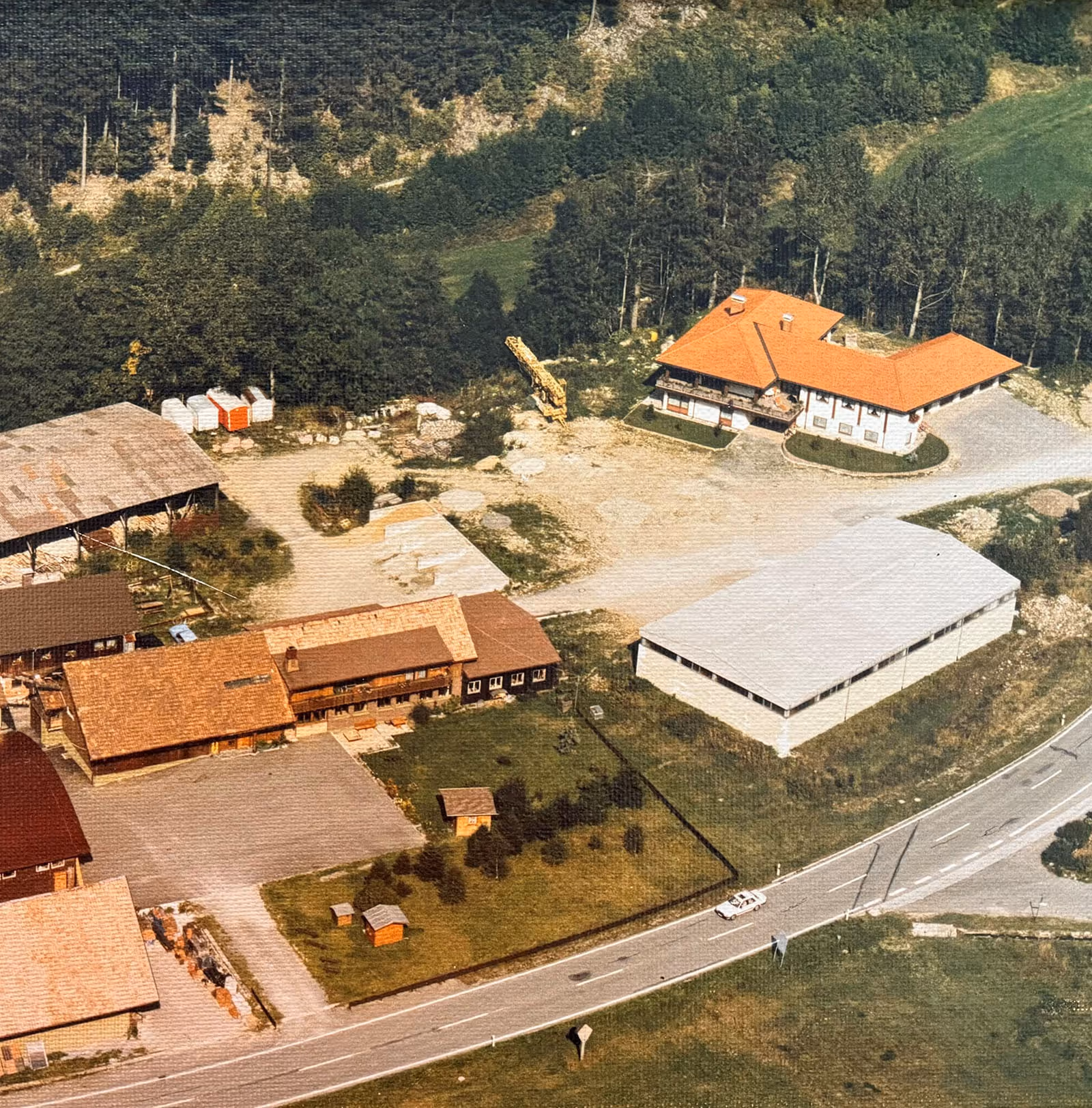 Altes Bild vom Bauhof der Firma Asal mit verschiedenen Gebäuden, Hallen und Lagerflächen, umgeben von Wald und Wiesen.