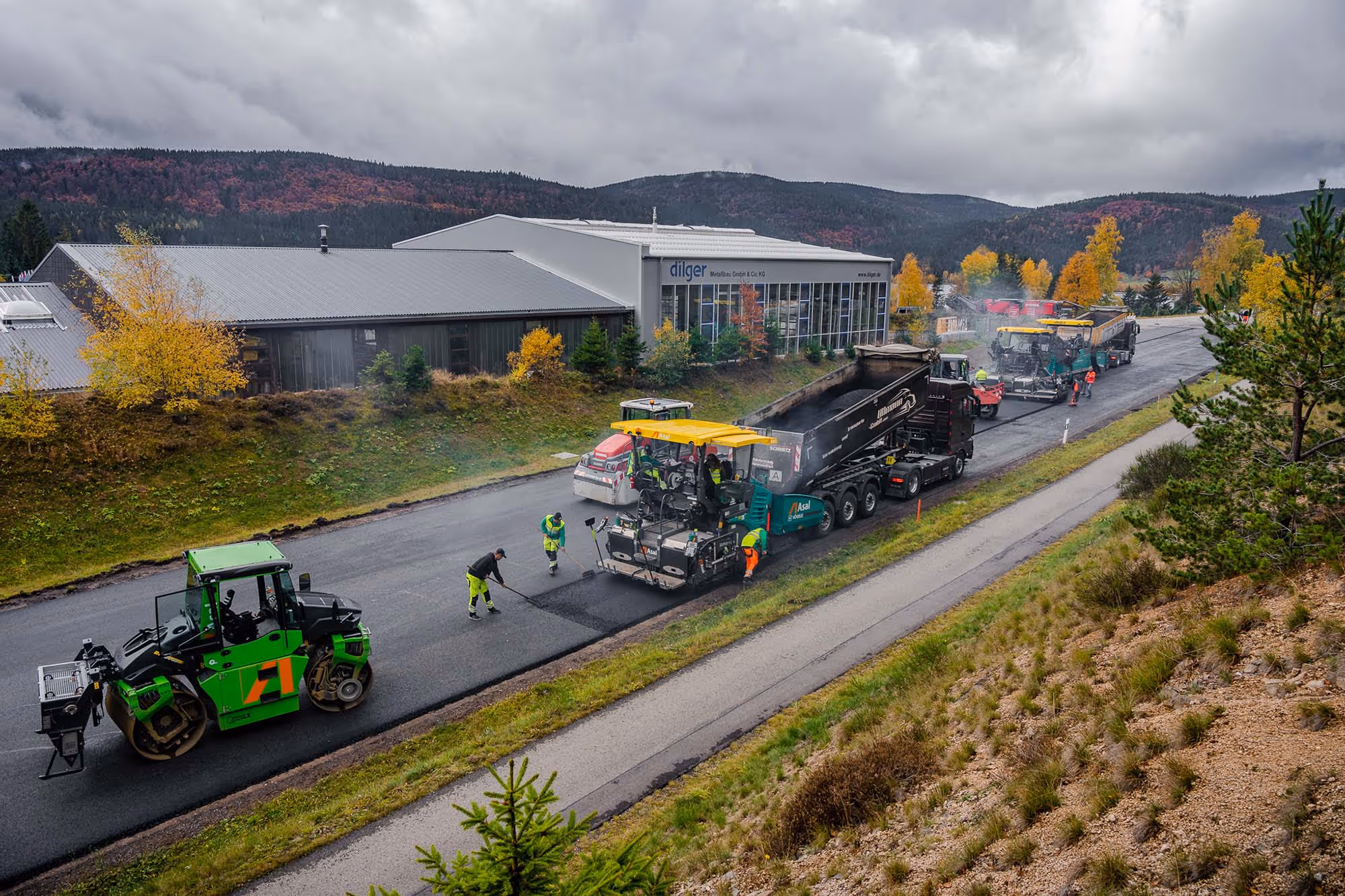 Kolonne beim Asphaltieren einer Straße, verschiedene Maschinen im Einsatz