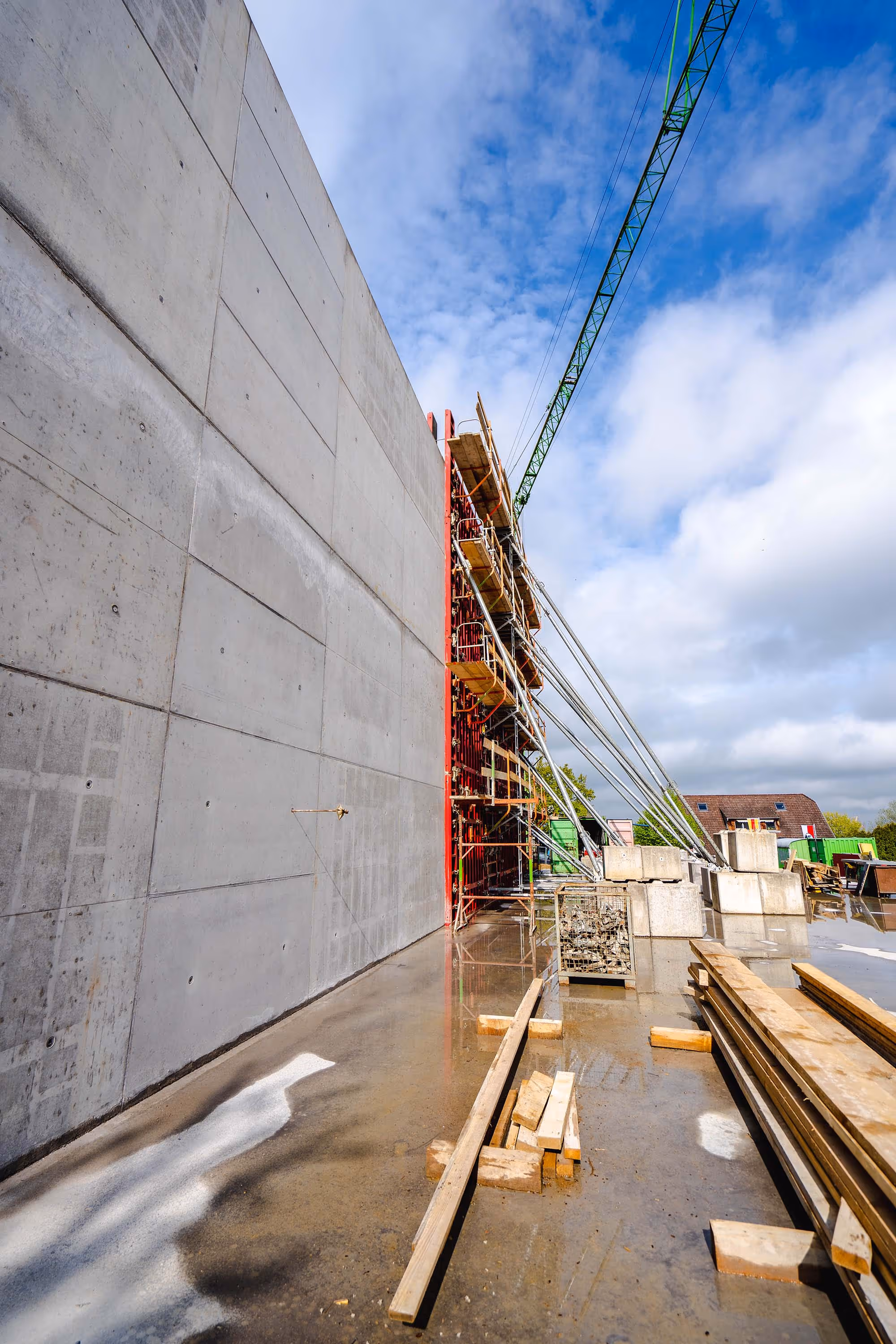 Großflächige Betonwand mit Gerüst und Schalung bei Ingenieurbauprojekt.