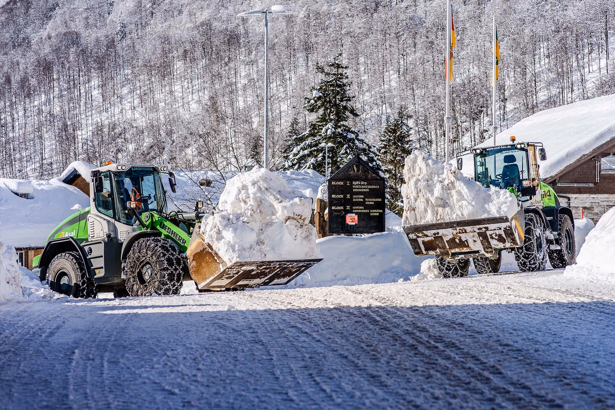 Zwei Radlader mit Schneeschaufeln transportieren große Schneemengen
