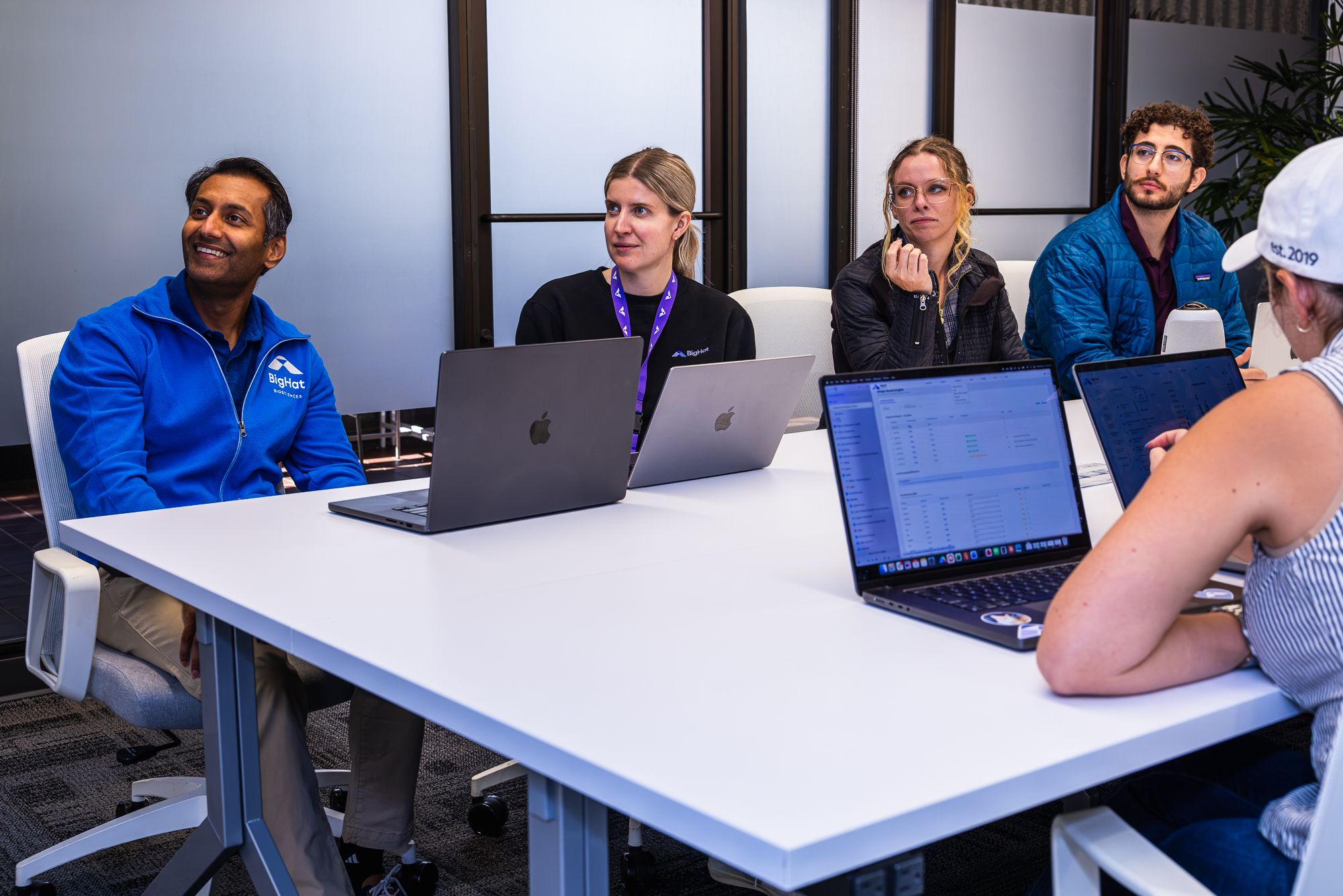 BigHat team members meeting around a conference table with laptops