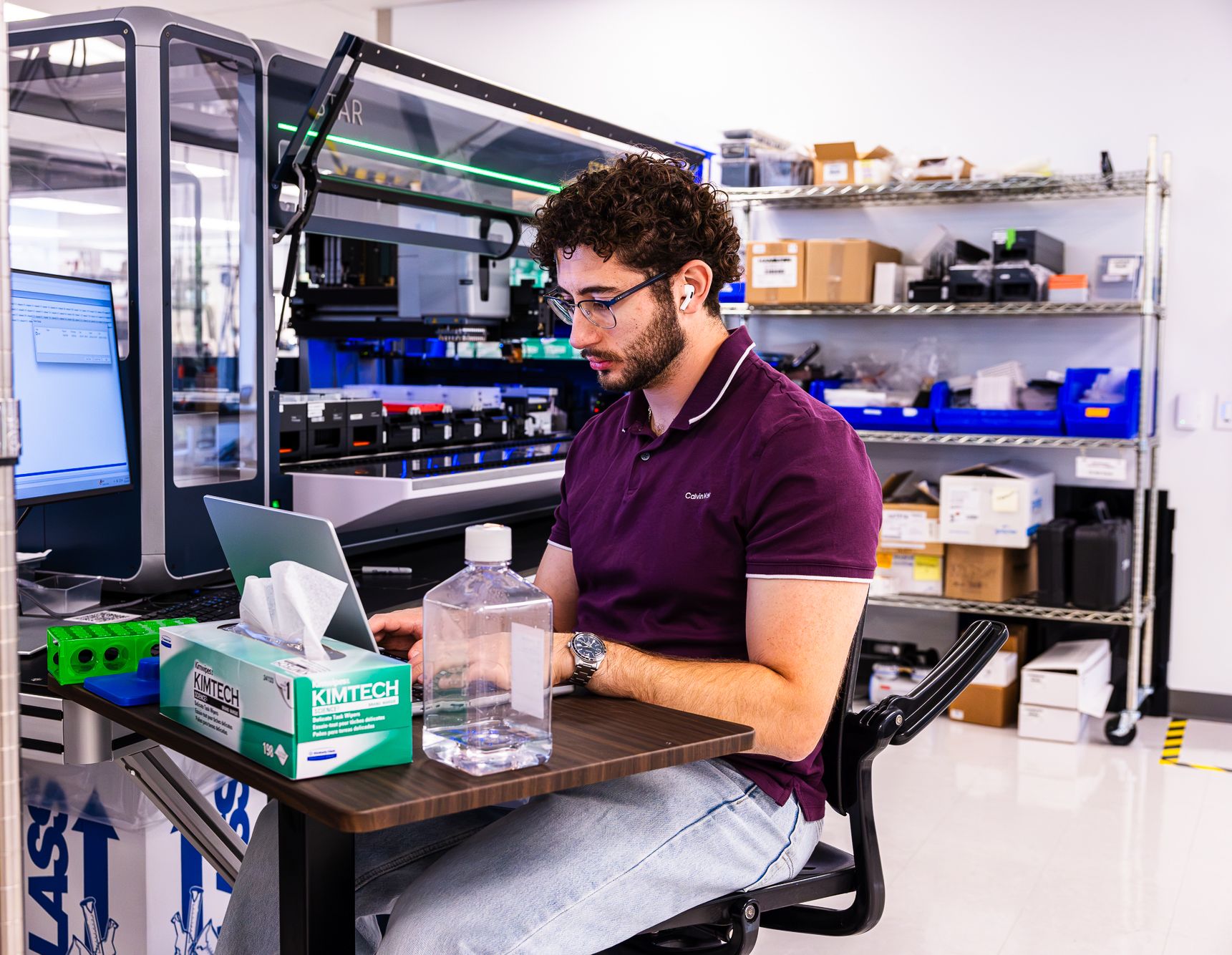 BigHat scientist working at a laptop beside lab automation equipment