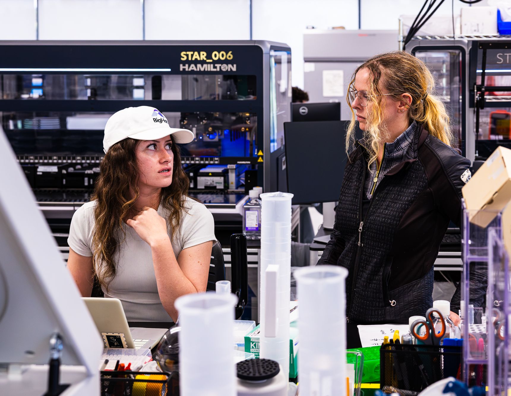 Two BigHat scientists talking beside automated lab instruments