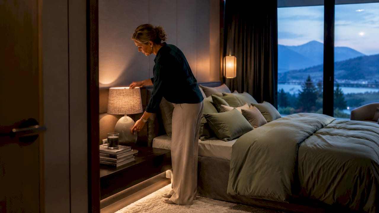 Woman adjusting layered lighting in luxury bedroom