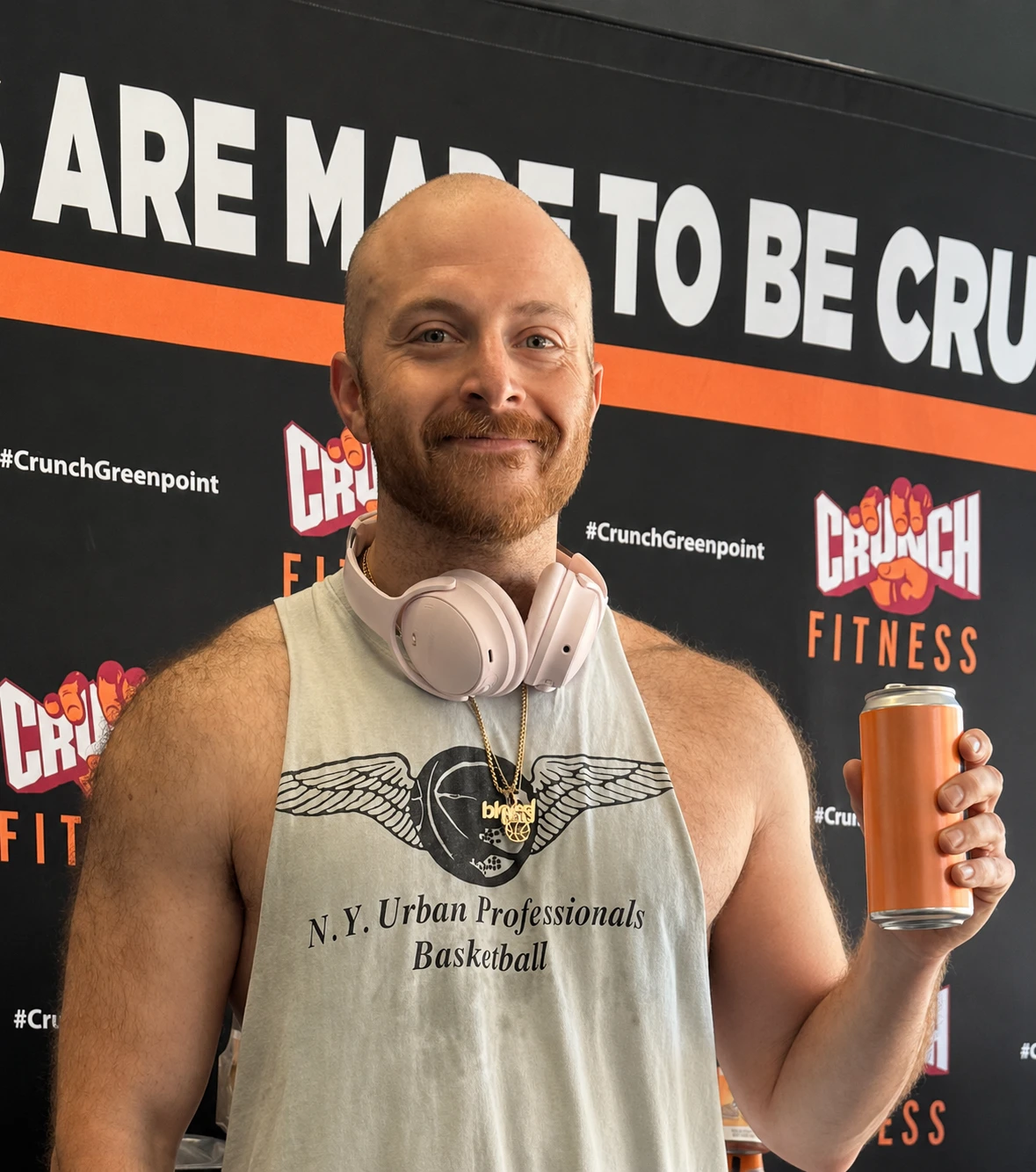 Crunch Fitness member holding a can of zero sugar tea at a branded backdrop