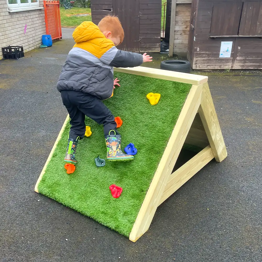 A nursery child scales the A-Frame Climibing Ramp