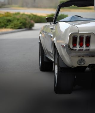 Weißer Mustang Sportwagen vor hellem Hintergrund.