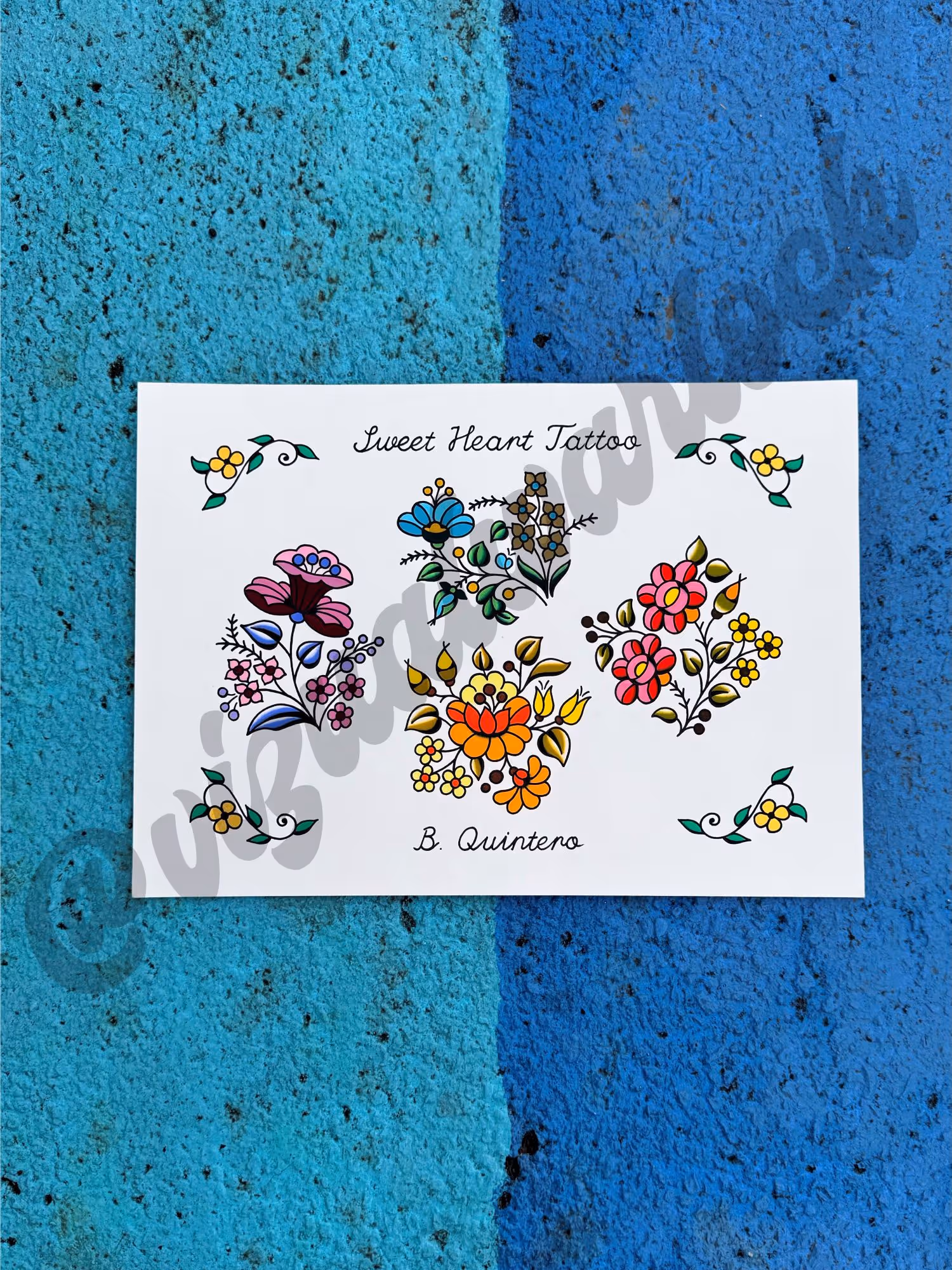 Flash sheet with four colorful floral tattoo designs and small yellow flowers in corners.