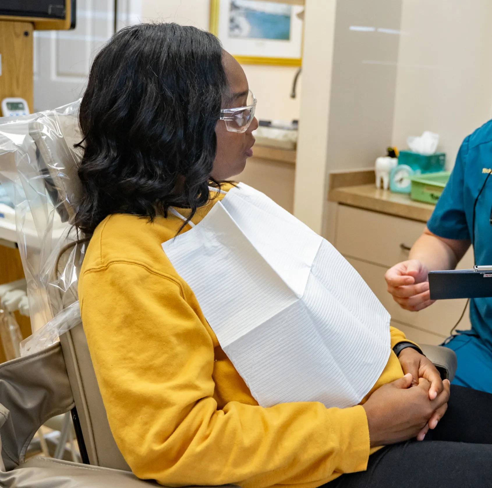 a man sitting in a chair next to a woman who is holding a clipboard
