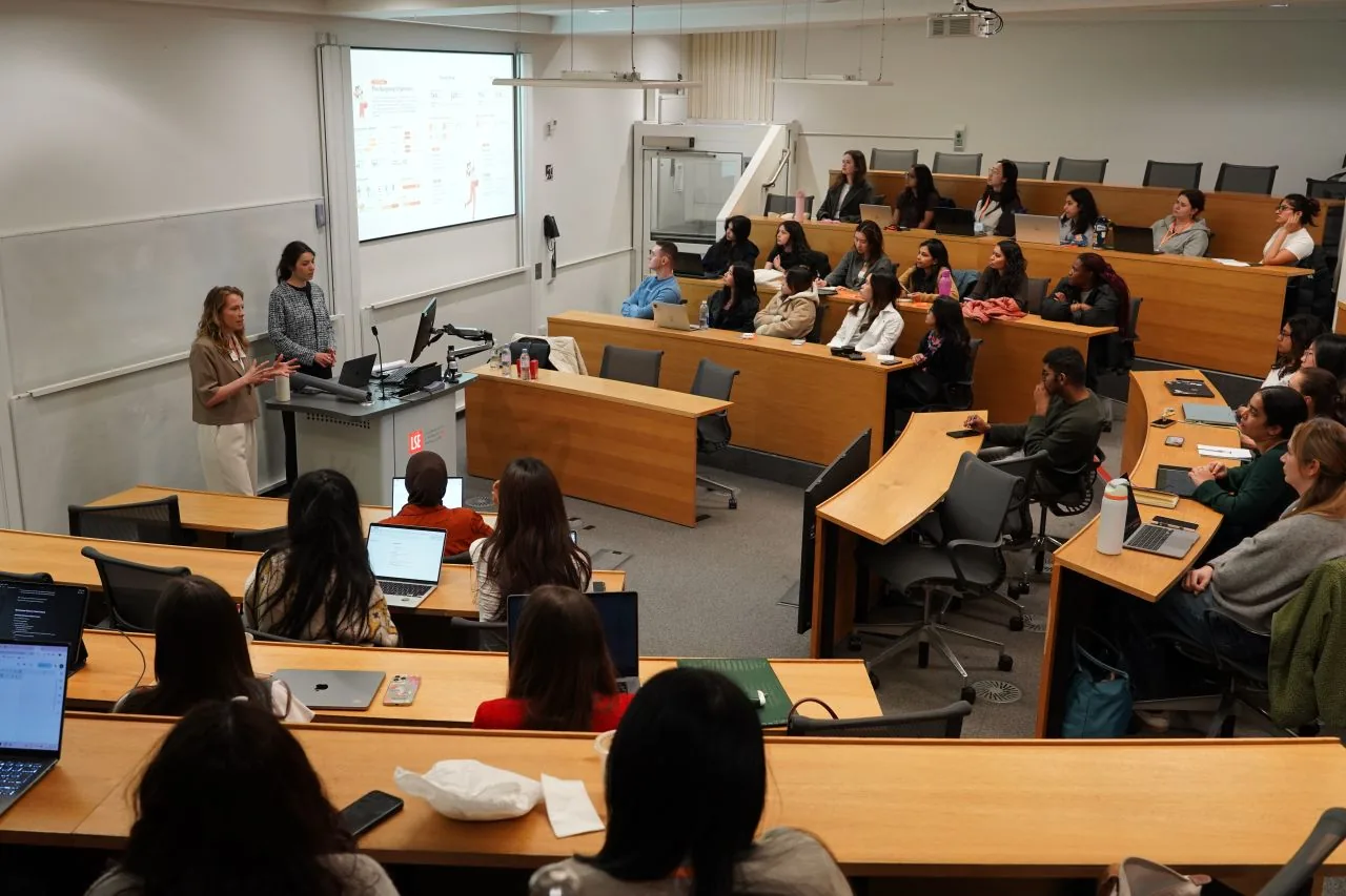 Two presenters speak to an audience in a university lecture hall