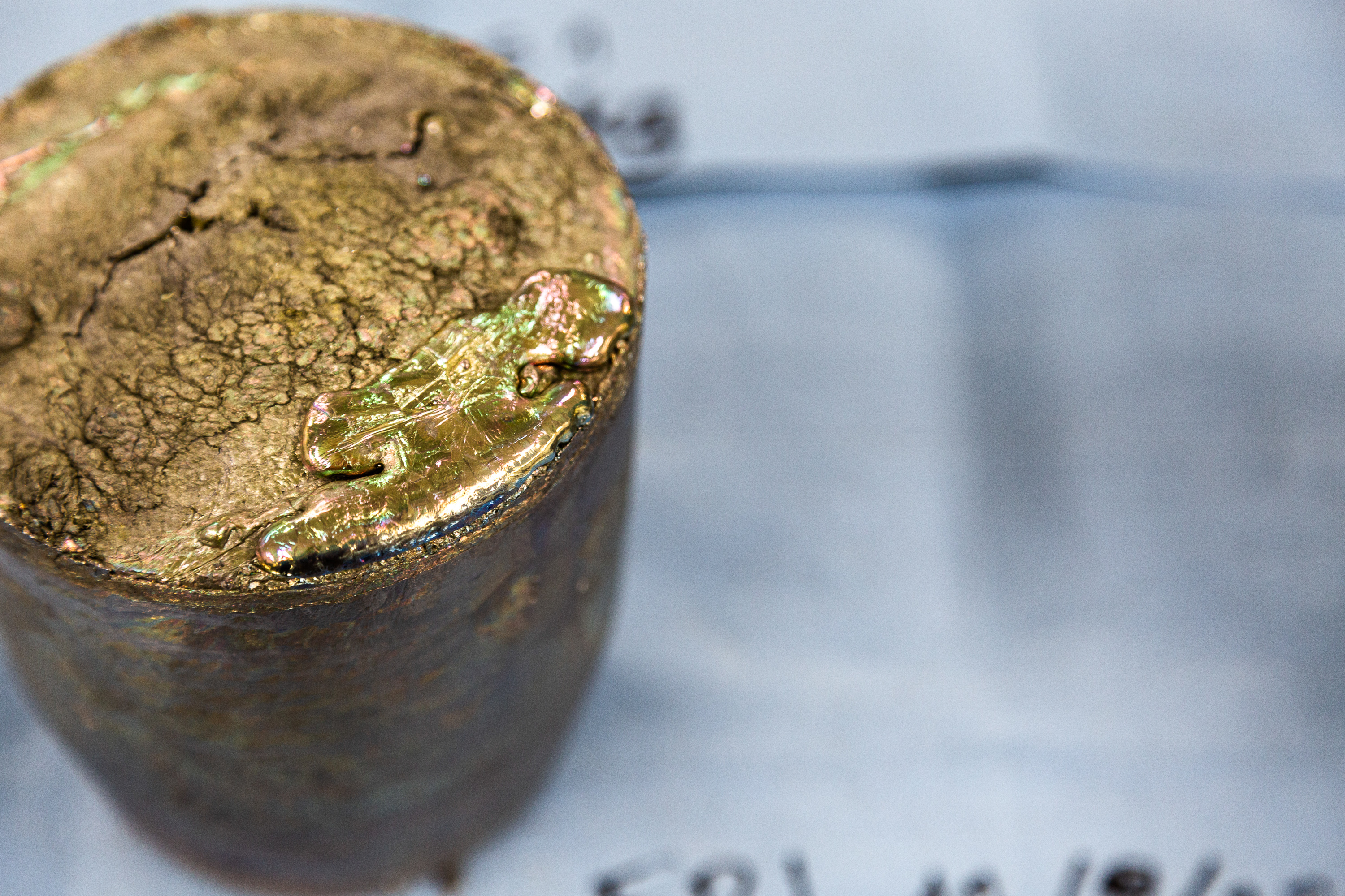 A bullet-shaped ingot of solidified bismuth sits upon a table.