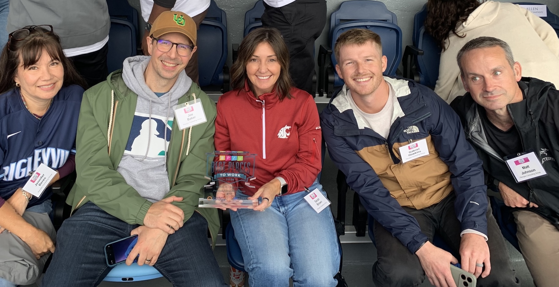 A smiling group of five seated people holding a Best Place to Work award.
