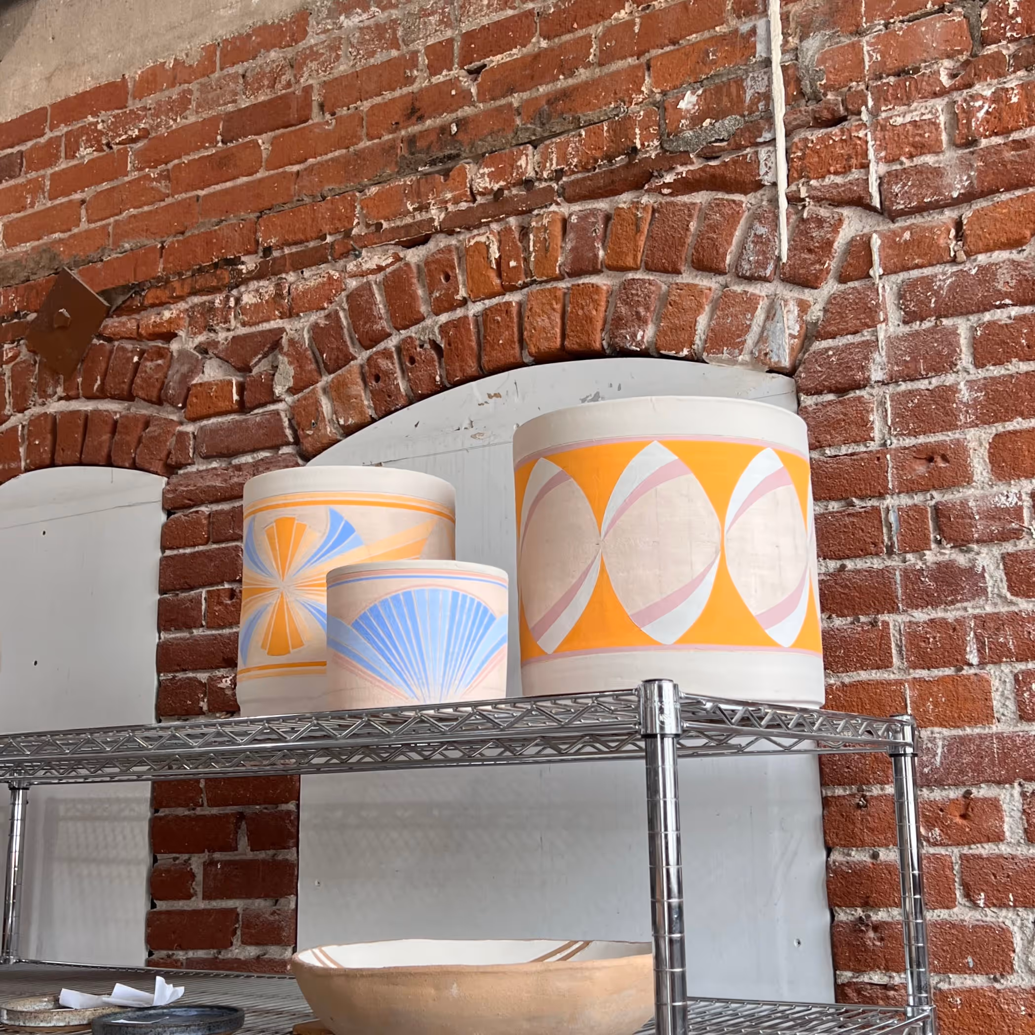 Hand-painted planters sitting on a shelf waiting to be glaze fired.