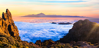 Impresionante vista panorámica de un mar de nubes desde las cumbres de Gran Canaria con la silueta del Teide al fondo durante el atardecer