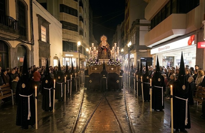 Procesión nocturna de Semana Santa en Las Palmas con cofrades vestidos de negro portando cirios y un trono religioso