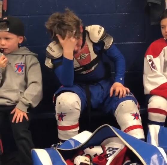 Young hockey player seated with his head in his hand during a difficult moment
